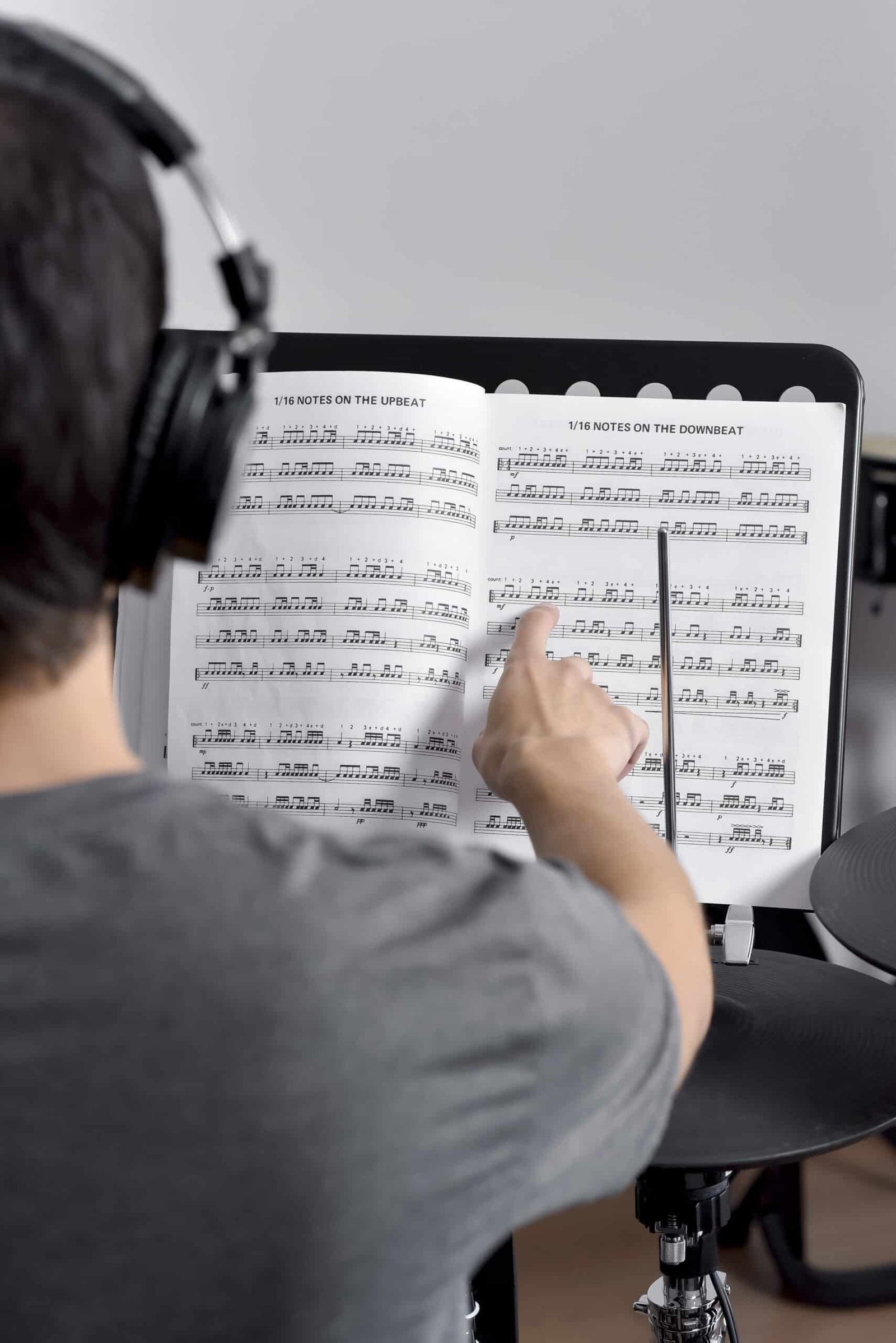 Professor Zeca Vieira sorrindo sentado atrás do instrumento em um estúdio com tratamento acústico preparado para aula de bateria.