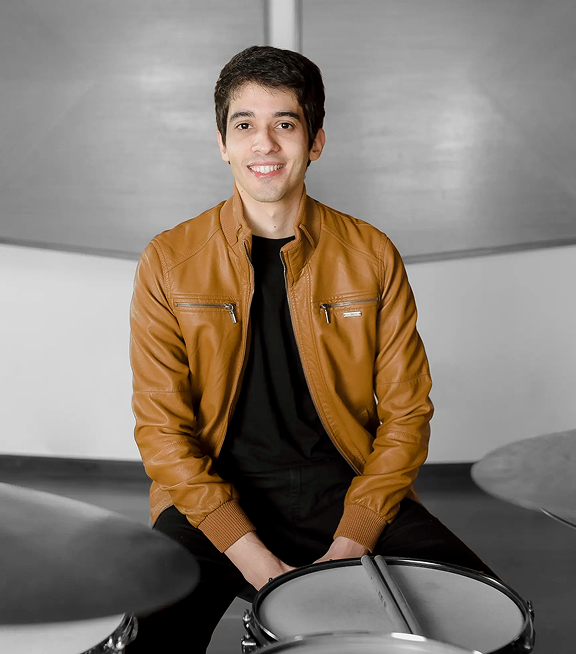 Monitor de computador exibindo o professor Zeca Vieira em seu estúdio dando aulas de bateria em valinhos, representando a interface e a qualidade visual das aulas de bateria online.