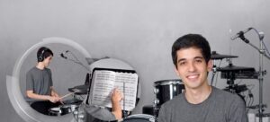 procurando por aula de bateria perto de mim? Um jovem instrutor de bateria sorridente posa para a câmera em seu estúdio musical equipado com uma bateria Roland e microfones. Inserções gráficas à esquerda mostram um aluno praticando com fones de ouvido e partituras de bateria, representando aulas de bateria em VAlinhos SP Campinas SP online e presenciais.